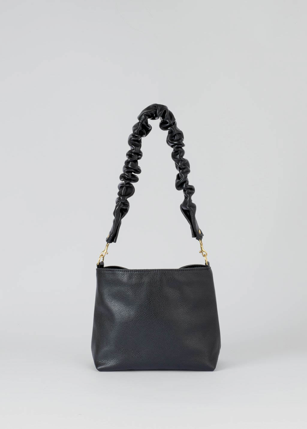 A black leather shoulder bag with a distinctive knotted, ruched strap and gold-tone hardware, photographed against a neutral light gray background.