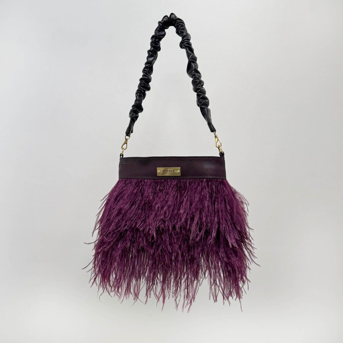 Purple feathered handbag with a chocolate brown handle on a white background